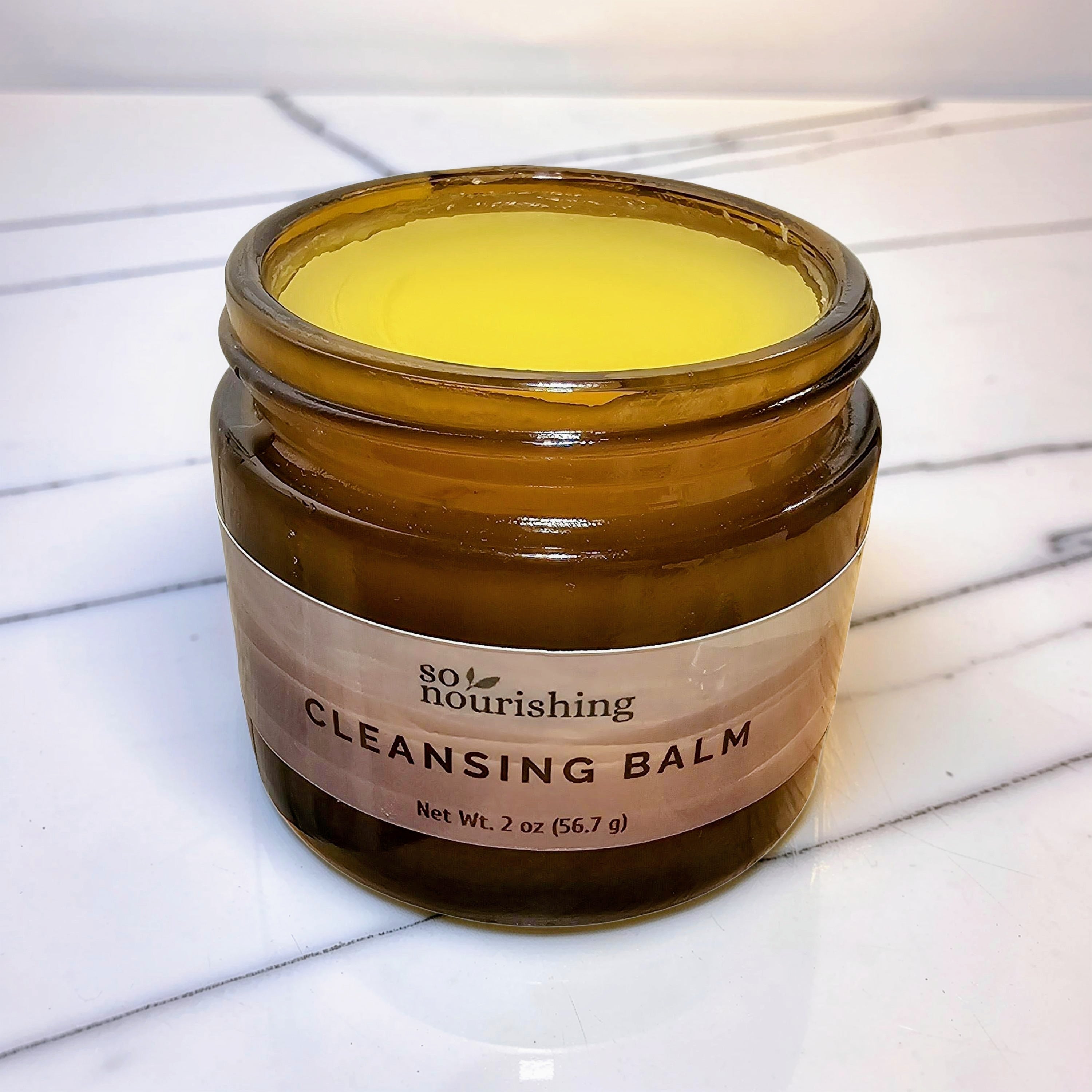 Jar of cleansing balm with a label on a marble surface