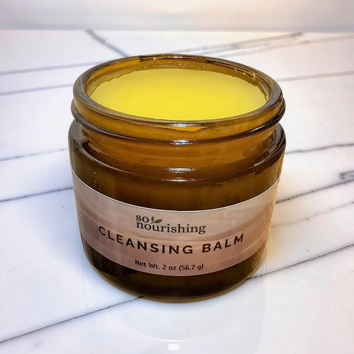 Jar of cleansing balm with a label on a marble surface